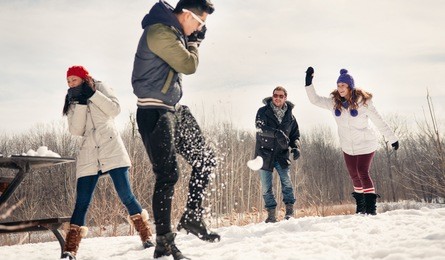 group of friends enjoying a snowball fight in the snow in winter