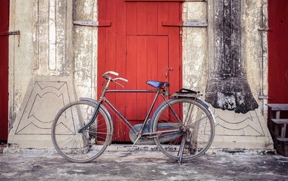 vintage retro bicycle with rusty,park in front of red wood door and old concrete wall at bagan,myanmar