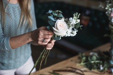 florist at work: pretty young blond woman making fashion modern bouquet of different flowers