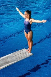female diver standing on the jumping board. preparing to jump into the pool