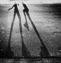 shadow of two people play fighting in the street toned with a high key filter effect 
