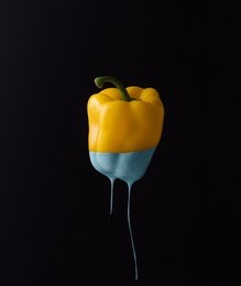 yellow bell pepper with dripping blue paint on dark background. minimal food concept.
