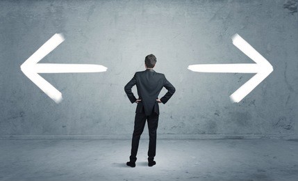 a businessman in doubt, having to shoose between two different choices indicated by arrows pointing in opposite direction concept