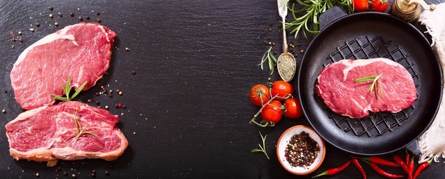 fresh meat with rosemary in a pan on dark board, top view with copy space.
