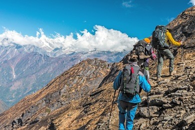 people traveling in mountains walking up on steep rocky path back view unrecognisable faces and copy space on left