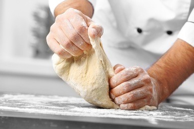 male hands preparing dough for pizza on table closeup