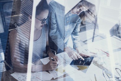 young womans working in modern design studio.two girls using electronic tablet on workplace.double exposure,skyscraper office building blurred background.horizontal