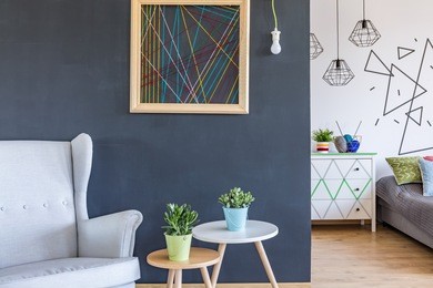cosy armchair and minimalistic coffee tables at the black wall background 