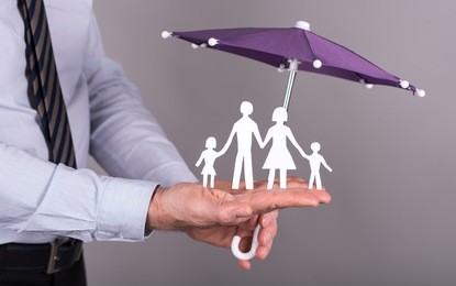 man holding an umbrella protecting a family