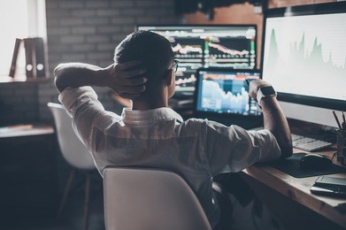 developing new approaches. rear view of young man in casual wear holding hand on the back of the head and working while sitting at the desk in creative office
