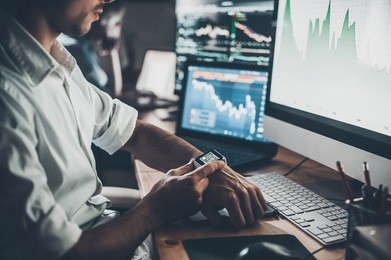 modern innovations. close-up of young businessman setting his smart watch while sitting at the desk in creative office 