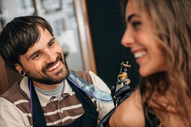 tattoo artist at work, having fun with client. toned image