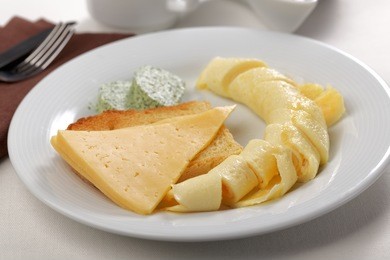 breakfast with omelet, toast, sliced cheese, and green butter