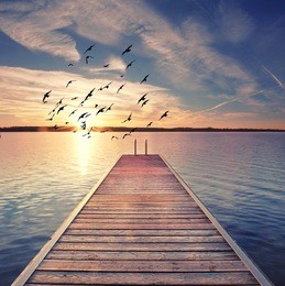 wooden pier with stairway to water, sunset at the beach