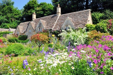 english country cottage with beautiful flowers garden in the sunshine in cotswolds, england, uk