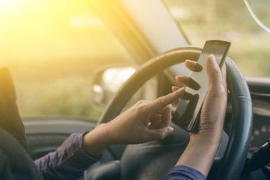 women driver with a cell phone in hand while driving
