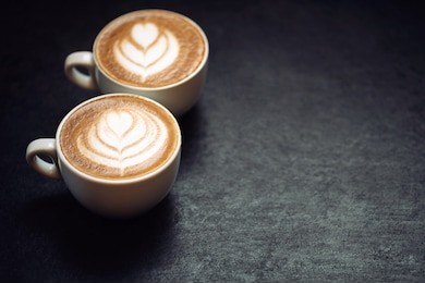 two cups of coffee on black rustic background with beautiful latte art
