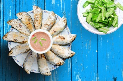 top view a dish of fried mackerel and shrimp chili paste serve on blue table with vegetable. it is a traditional thai food