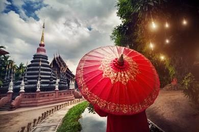 woman tourist with red traditional thai umbrella in black temple wat phan tao in chiang mai, thailand