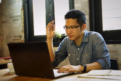 man in casual dress in working on his computer. he is  concentrating on screen.