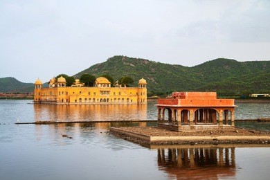 jaipur, india. jal mahal palace in the evening in jaipur, india. popular landmark surrounded by water. mountains at the background