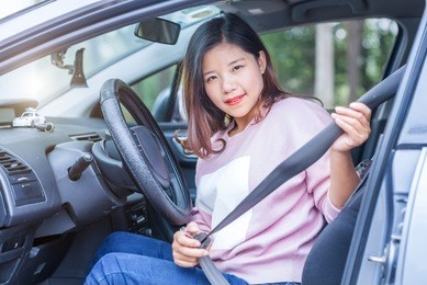 safety first. beautiful asian lady fastening car seat belt.