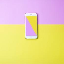 yellow and pink color on smart phone screen on colored background.  minimal concept. flat lay. top view. 