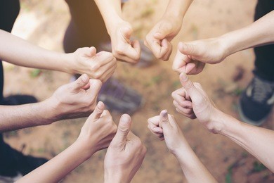 team work concept : group of diverse hands together thump up of young people in the nature.