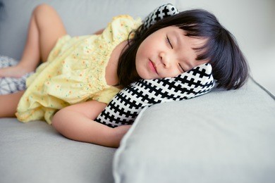 adorable little girl smile and sleep in the sofa bed.