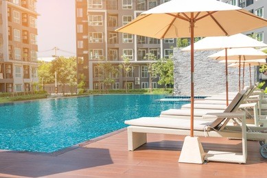 relaxing rattan chairs with pillows beside swimming pool