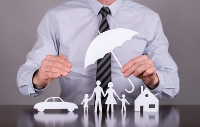 man holding an umbrella protecting a family, a house and a car