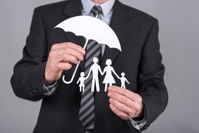 man holding an umbrella protecting a family