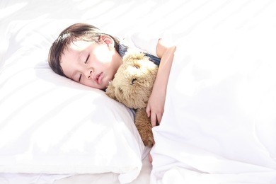 little asian girl sleeping with her toy teddy bear on the bed, new family and baby healthy concept