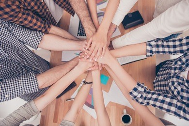 close up of group of businesspeople putting their hands on top of each other