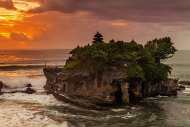 the pilgrimage temple of pura tanah lot is perched dramatically on a large coastal rock.