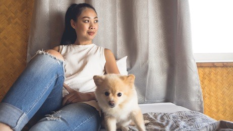 asian woman relax on bed with her dog in bamboo bedroom.
