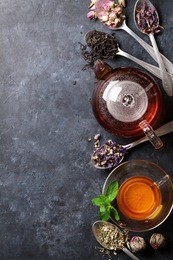 tea cup, teapot and assortment of dry tea in spoons on stone table. top view with copy space