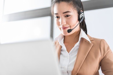 portrait of happy smiling female customer support phone operator at workplace. asian