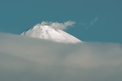 the top of the volcano smoldering above the clouds