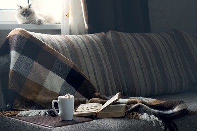 cup of hot coffee with marmalade book points the blanket on the couch