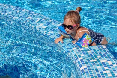 happy baby girl playing in pool on a hot summer day during vacation