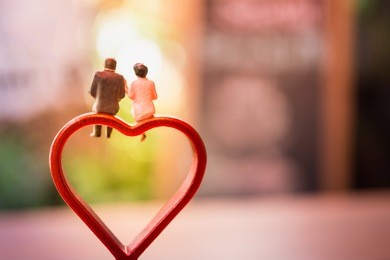 miniature of a women and a man in love sitting on heart sign bench with bokeh light copyspace, couple in love and pre-wedding background concept