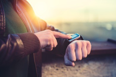 man wearing leather jacket using smart watch on the rooftop
