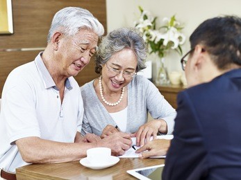 happy senior asian couple signing a contract agreement in front a salesperson.