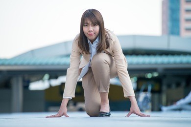 young asia businesswoman in business look dressing taking position for start in a race with urban business area background.