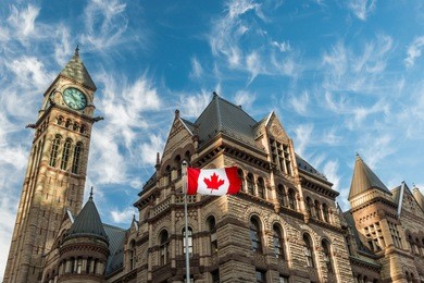 the canadian flag flies before the old city hall in toronto, canada.