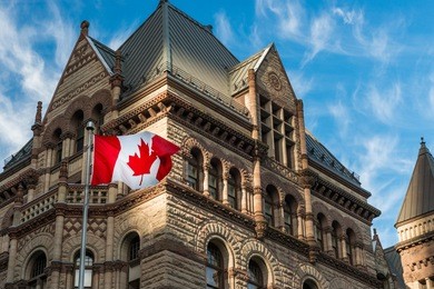 the canadian flag flies before the old city hall in toronto, canada.