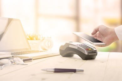 mobile payments concept with edc machine or credit card terminal with computer laptop and glasses. warm toning effect.