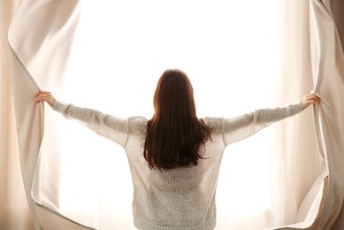 girl opening curtains