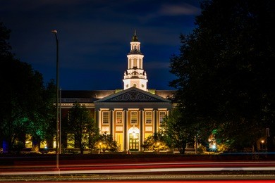 traffic on soldiers field road and building at harvard business school at night, in boston, massachusetts.
